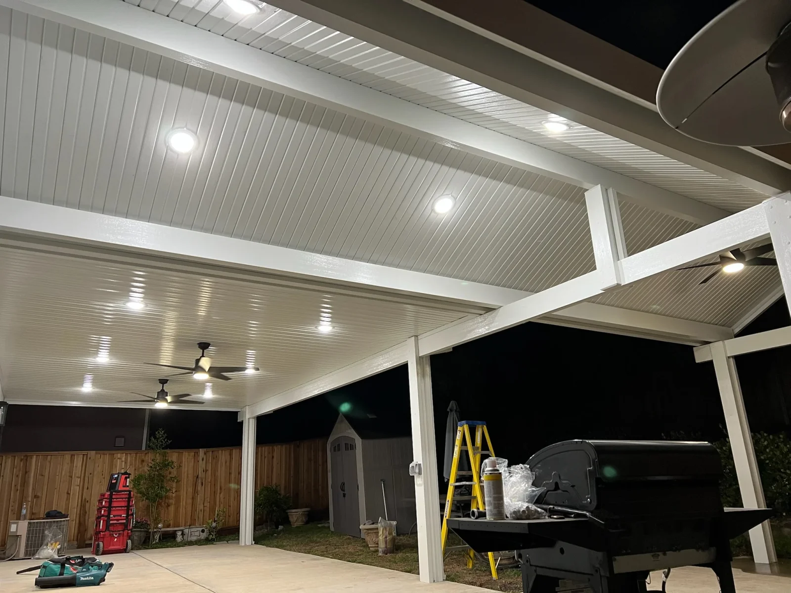 White aluminum louvered gazebo with LED recessed lights and ceiling fans over concrete patio