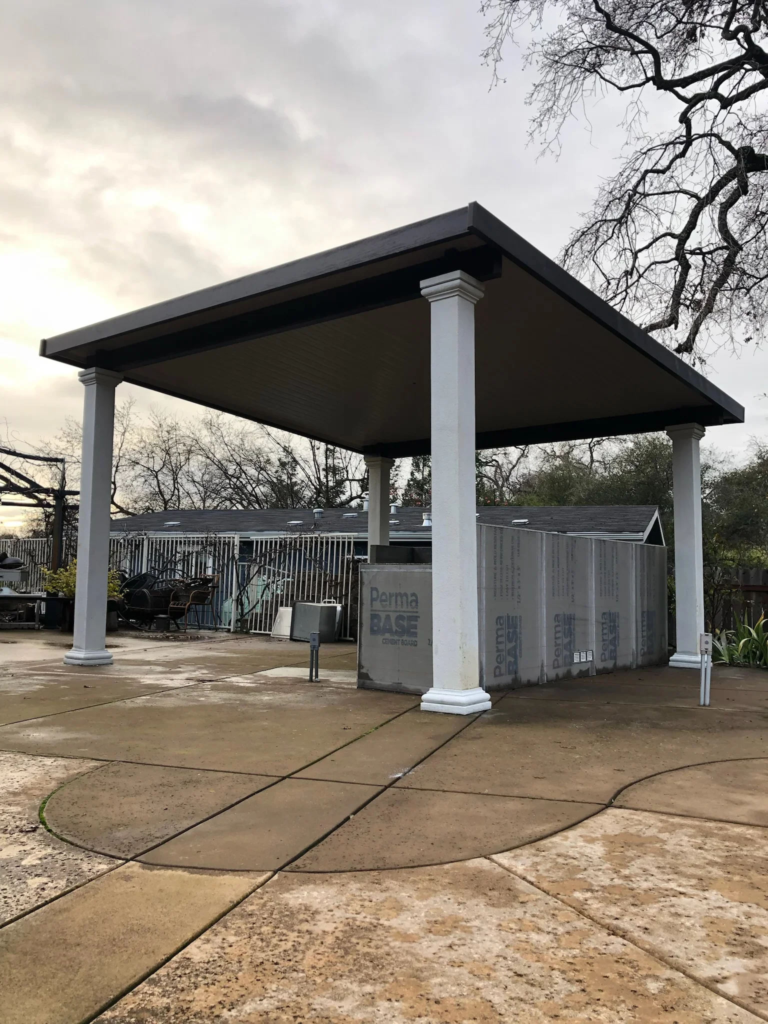 Black aluminum gazebo with white columns over stamped concrete patio