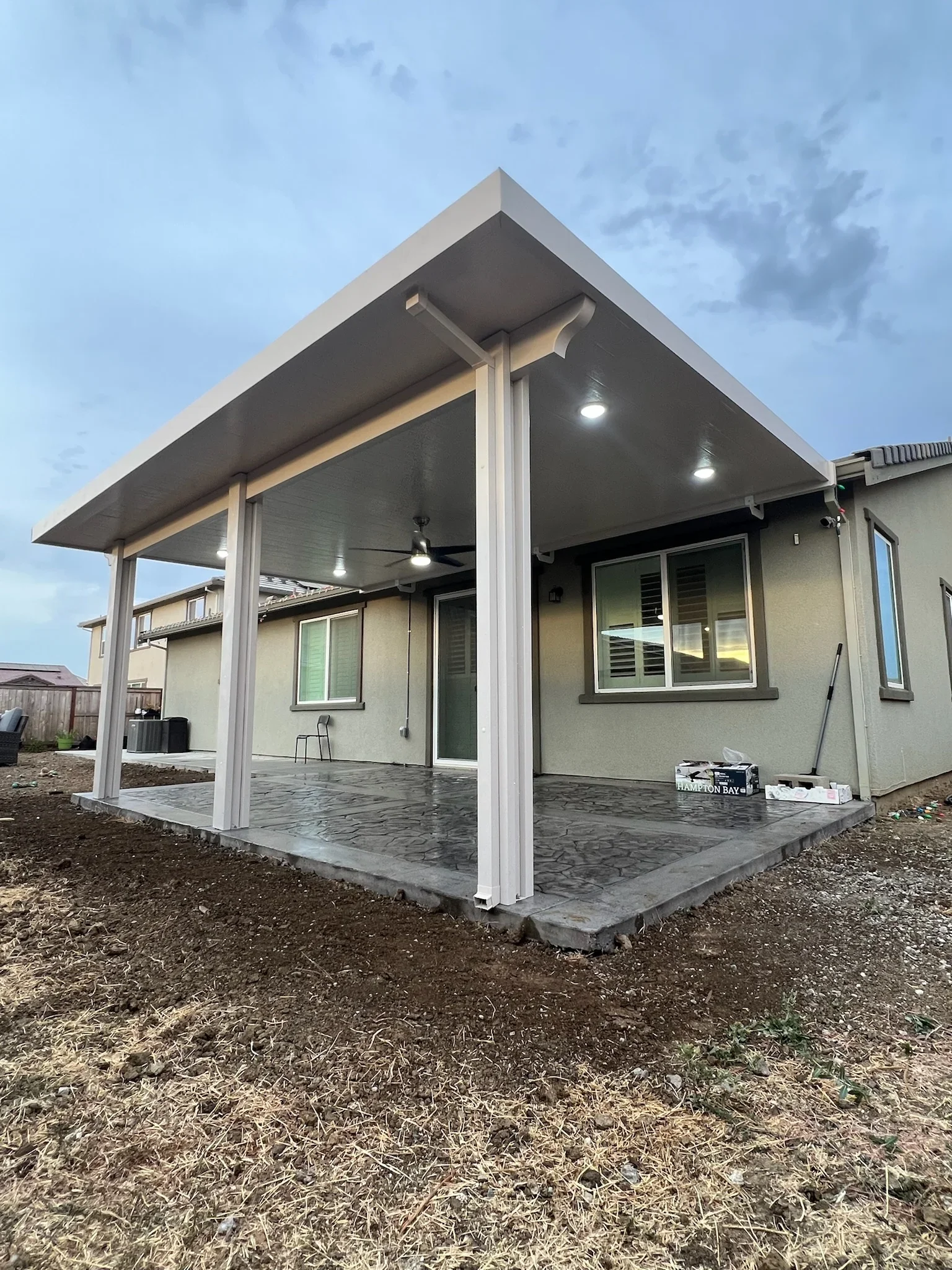 White aluminum gazebo with dark gray ceiling, LED lights, and concrete foundation attached to residential home