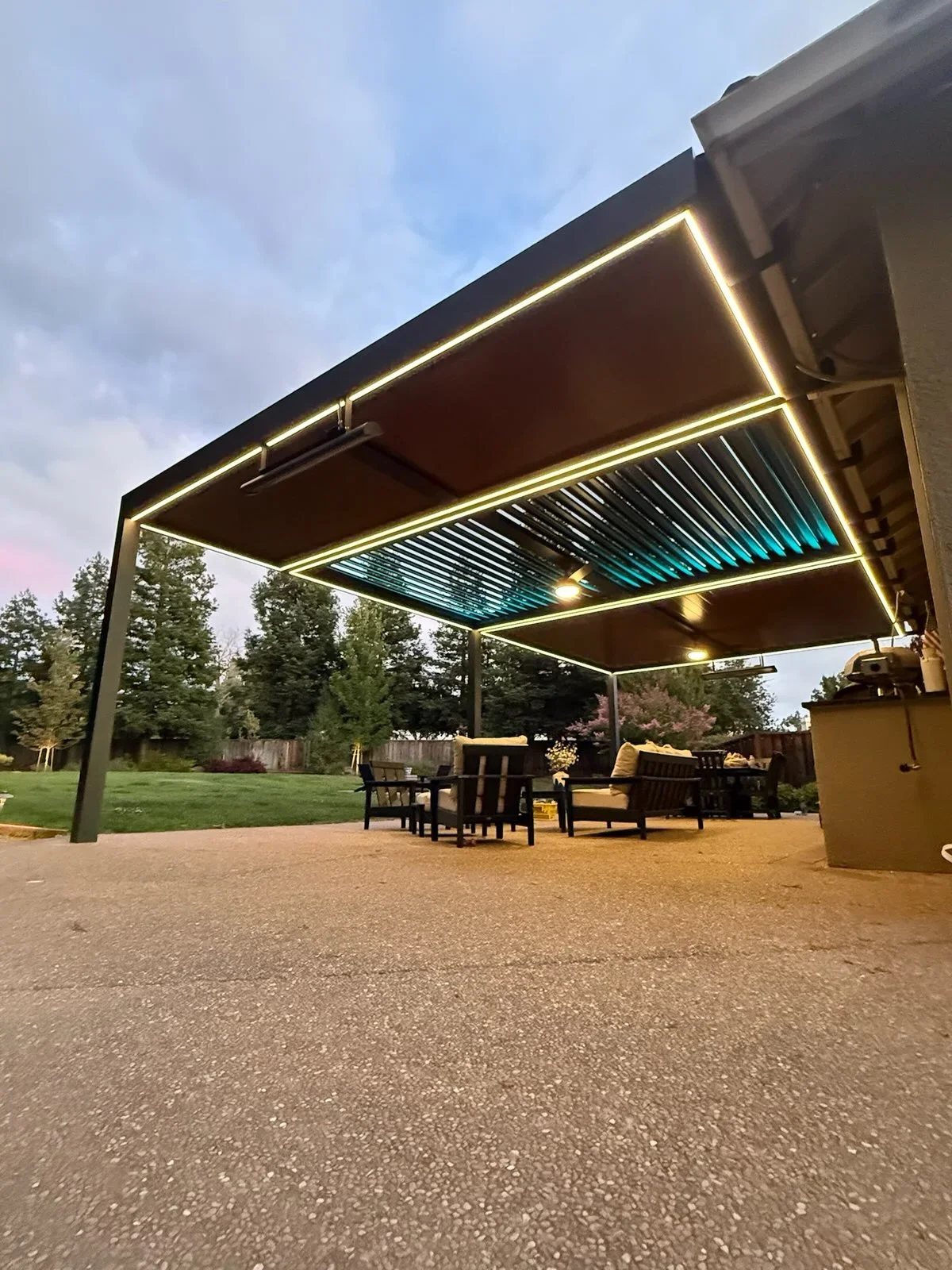 Steel pergola with motorized louvered roof and LED lighting over patio seating area