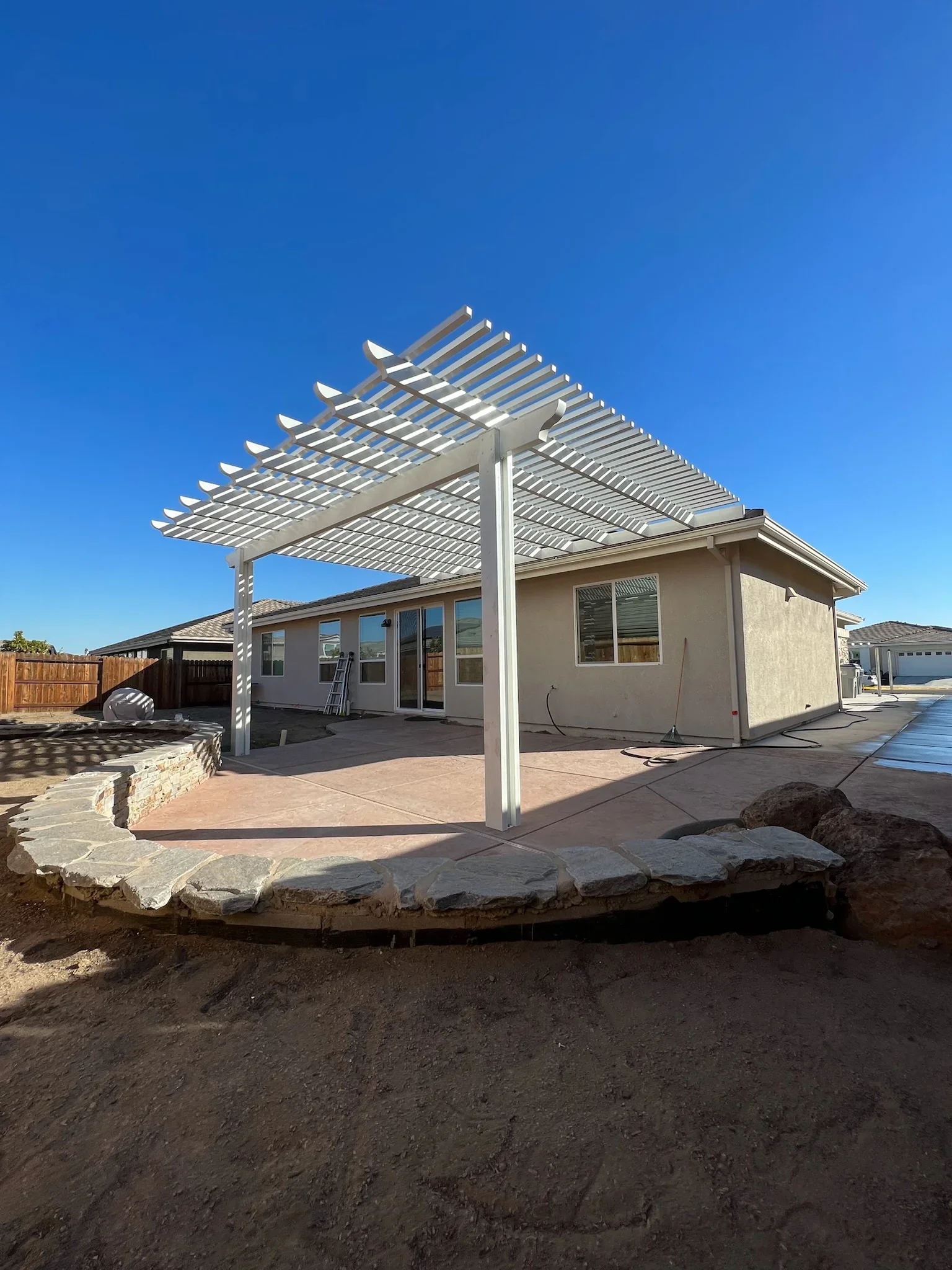 White aluminum louvered pergola over stamped concrete patio with adjustable slats