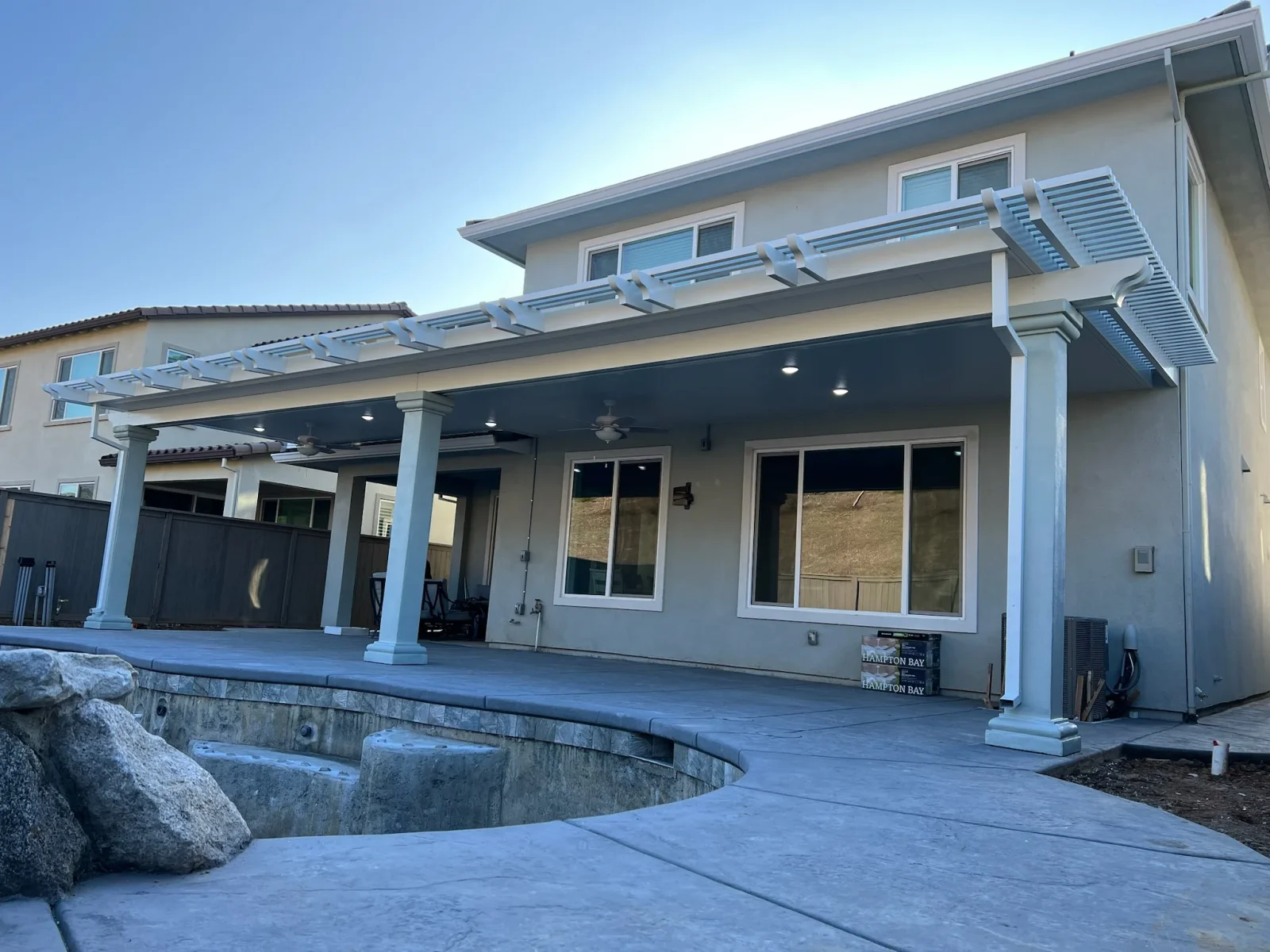 White aluminum pergola with adjustable louver panels over concrete patio with recessed lighting