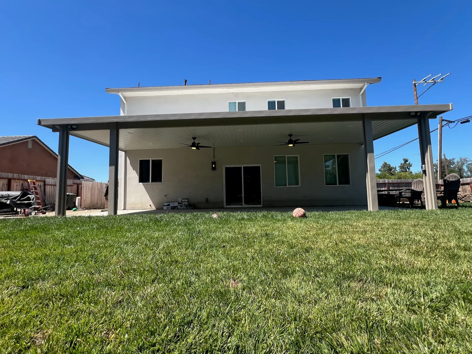 Steel pergola with metal roof, ceiling fans, and white trim over residential patio
