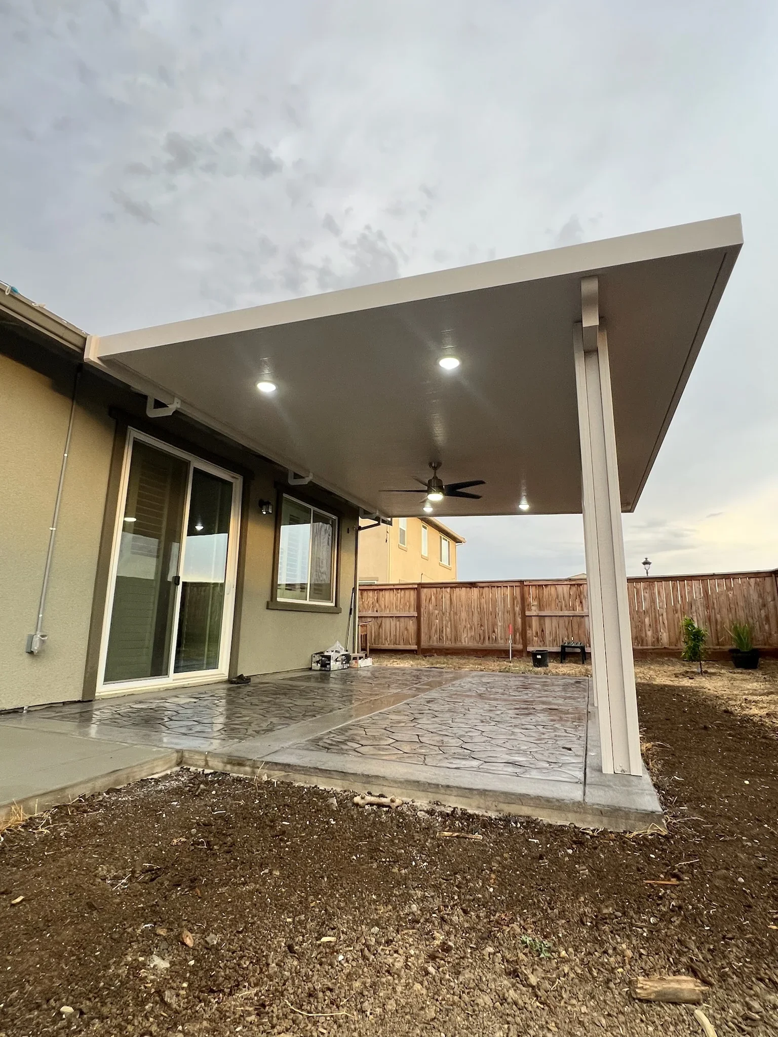 Aluminum patio cover with recessed lighting, ceiling fan, and stamped concrete flooring